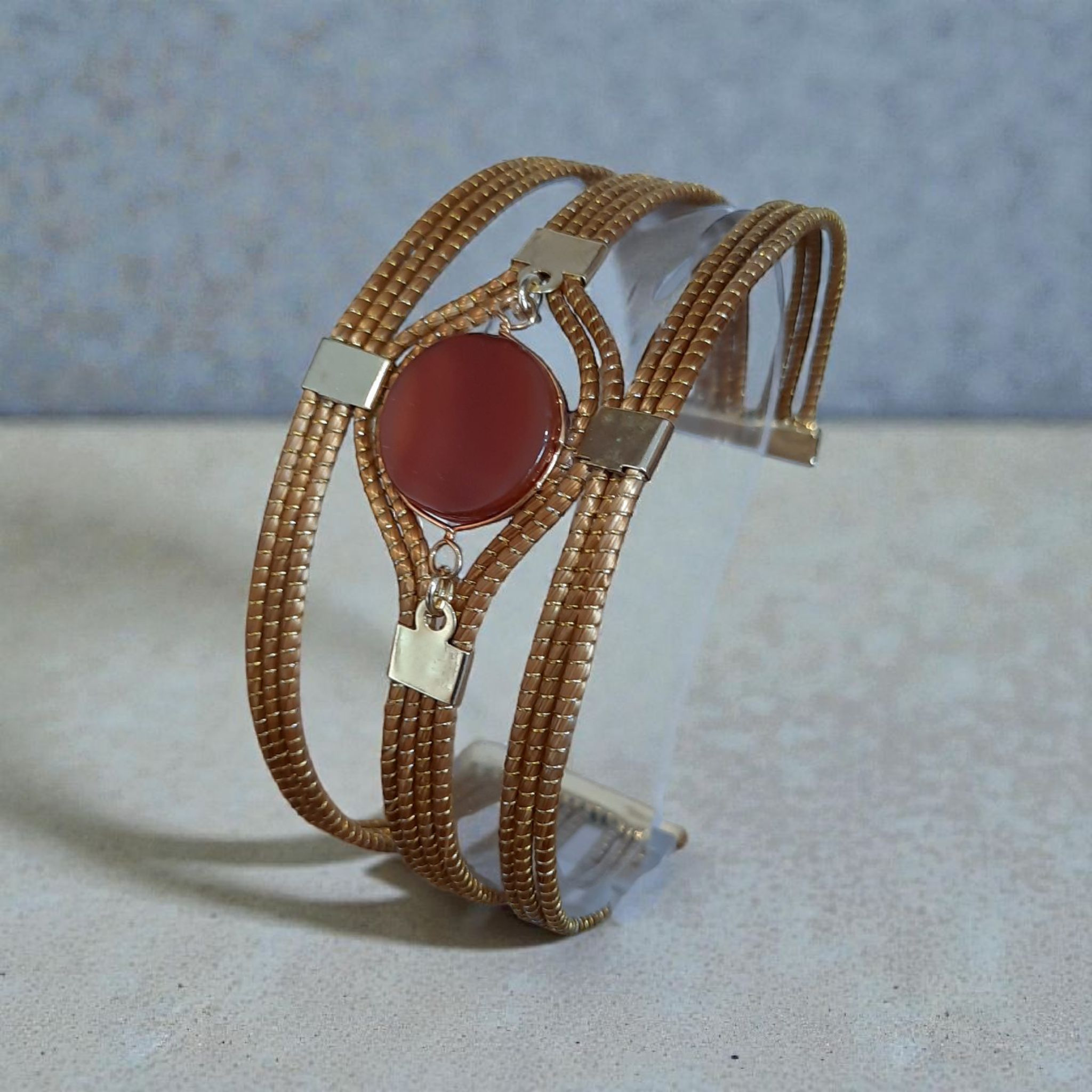 Bracelet multi-rangs en capim dourado doré avec pierre ronde rouge au centre et charms argentés, bijou artisanal à Gérardmer.